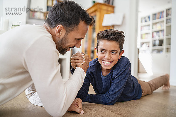 Vater und Sohn liegen zu Hause auf dem Boden und machen Armdrücken
