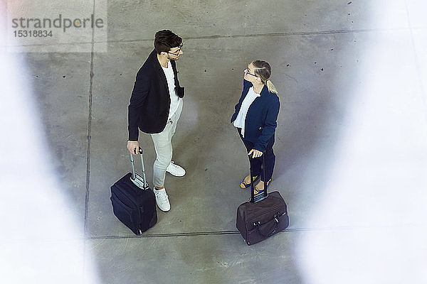Zwei junge Geschäftspartner mit Gepäck im Gespräch
