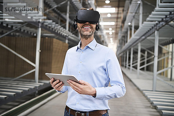 Geschäftsmann mit Tablette mit VR-Brille in der Fabrik