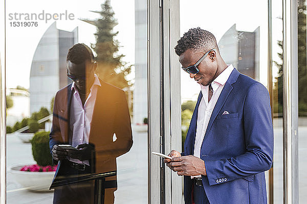 Junger Geschäftsmann benutzt draußen sein Smartphone