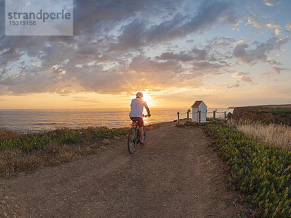 Portugal  Alentejo  älterer Mann auf E-Bike bei Sonnenuntergang