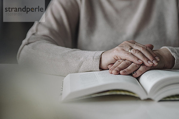 Nahaufnahme einer älteren Frau  die ein Buch auf dem Tisch liest