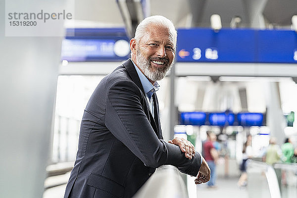 Porträt eines lächelnden reifen Geschäftsmannes auf dem Bahnsteig