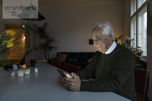 Lächelnder älterer Mann benutzt Tablette zu Hause