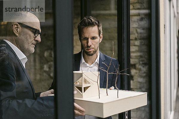 Senior- und mittel-erwachsener Geschäftsmann mit Architekturmodell
