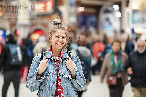 Porträt einer glücklichen jungen Frau am Bahnhof