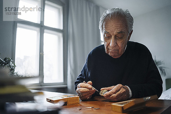 Älterer Mann repariert zu Hause eine Uhr