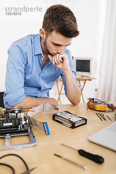 Techniker  der einen Desktop-Computer repariert und überlegt  wie er die Festplatte reparieren kann