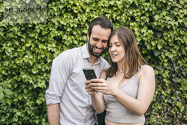 Glückliches junges Paar  das sich ein Handy teilt