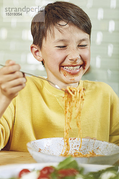 Unordentlicher Junge isst Spaghetti mit Tomatensauce