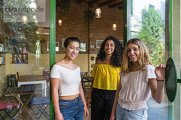 Porträt von drei lächelnden jungen Frauen in einem Cafe