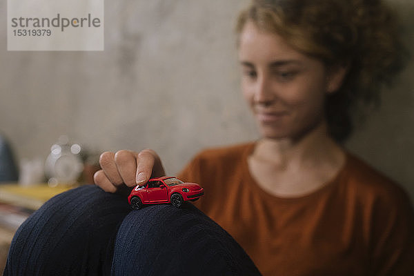 Junge Frau spielt mit rotem Spielzeugauto