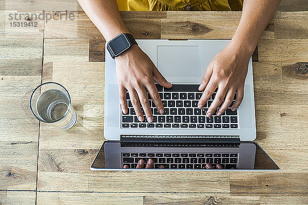 Hände einer Frau beim Tippen auf der Tastatur eines Laptops  Draufsicht