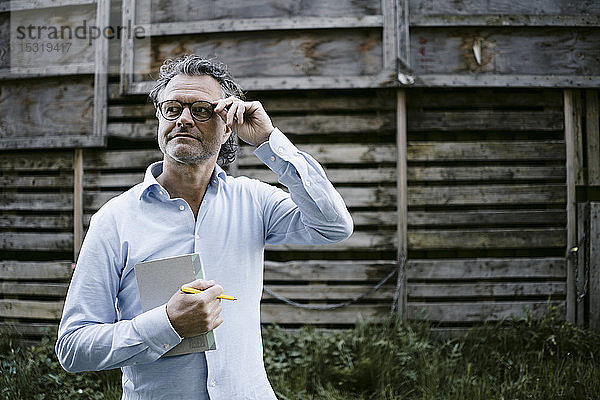Bildnis eines reifen Mannes mit Notizbuch  Hand auf Brille