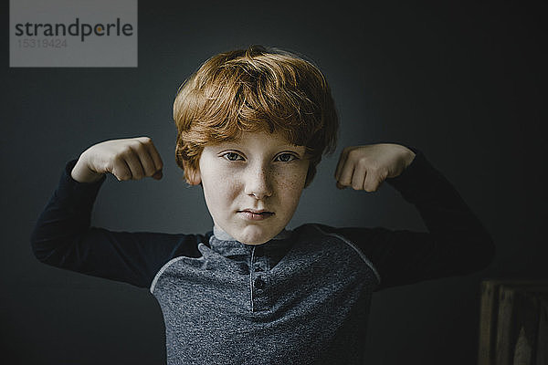Porträt eines rothaarigen Jungen mit gebeugten Muskeln