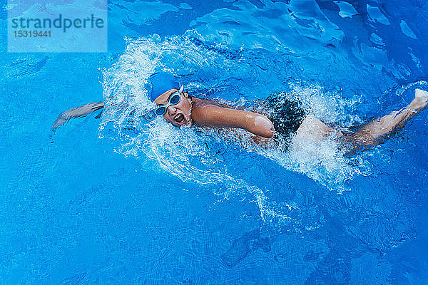 Paralympischer junger Schwimmer krabbelt in einem Becken