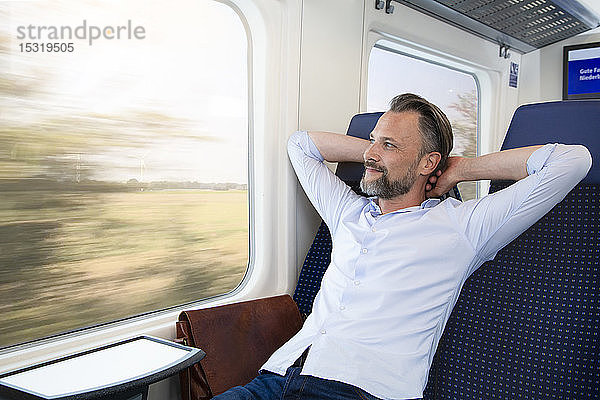 Reifer Mann sitzt im Zug und entspannt sich