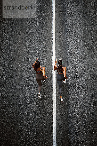 Draufsicht auf zwei sportliche Zwillingsschwestern  die auf einer Straße laufen
