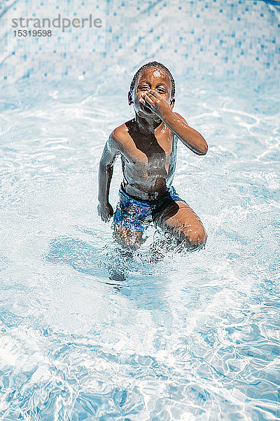 Afrikanisches Kind amüsiert sich im Schwimmbad  hält sich die Nase zu