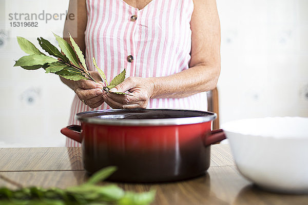 Frau benutzt Lorbeer zum Kochen in der Küche