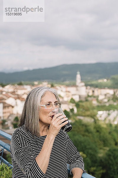 Porträt einer älteren Frau  die auf ihrer Dachterrasse Kaffee trinkt  Belluno  Italien