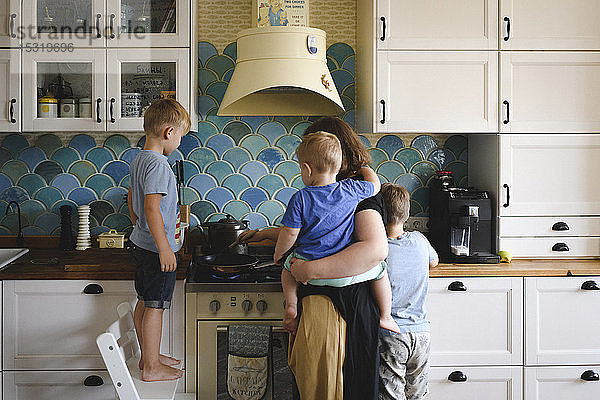 Mutter kocht mit ihren drei Söhnen in der Küche
