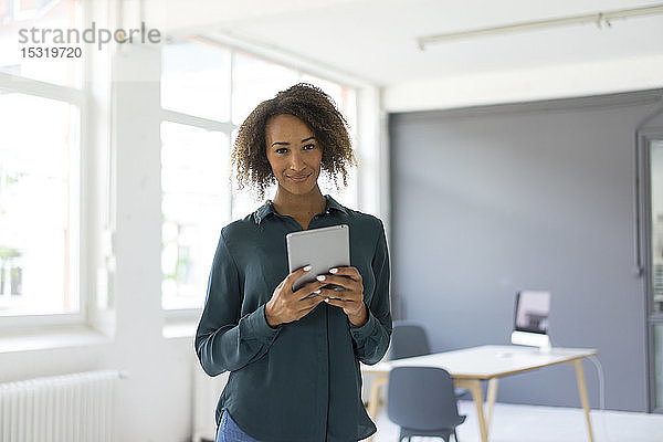 Porträt einer lächelnden jungen Geschäftsfrau mit digitalem Tablet im Büro