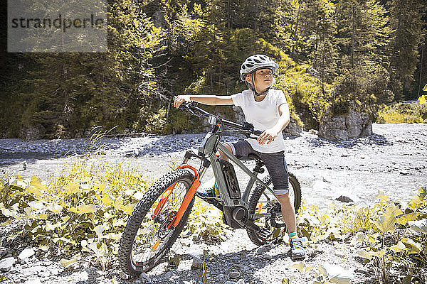 Junge in den Bergen mit seinem E-Mountainbike