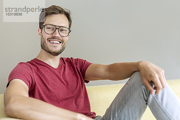 Porträt eines glücklichen Mannes auf einer Couch sitzend