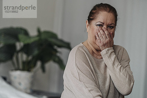 Porträt einer älteren Frau  die den Mund mit der Hand bedeckt