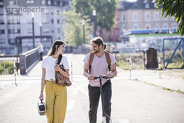 Junges Paar mit Elektroroller auf der Straße