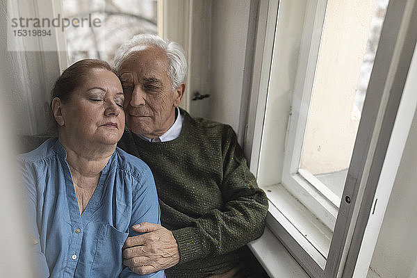 Porträt eines liebevollen älteren Ehepaares am Fenster