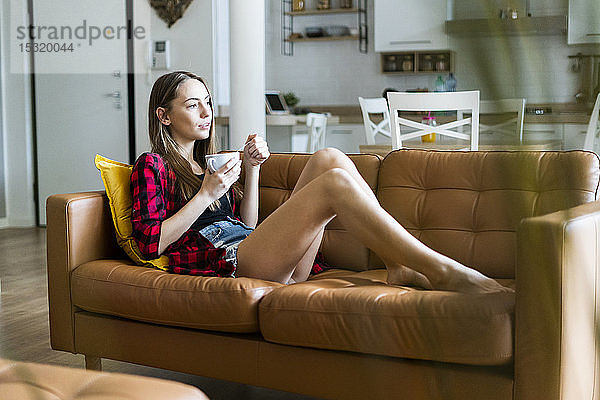 Entspannte junge Frau isst zu Hause im Wohnzimmer Müsli