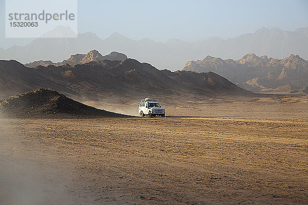 Geländewagen auf Staub in der Wüste gegen den Himmel bei Sonnenuntergang