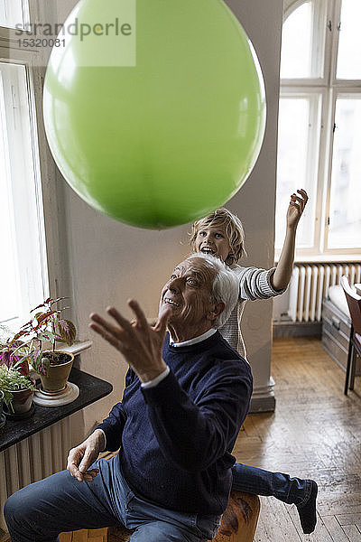 Glücklicher Großvater und Enkel spielen zu Hause mit dem Ballon