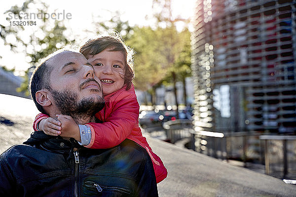 Zweijähriges Mädchen umarmt im Winter ihren Vater in der Stadt. Barcelona  Spanien