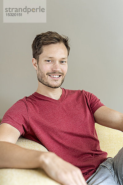 Porträt eines lächelnden Mannes auf einer Couch sitzend