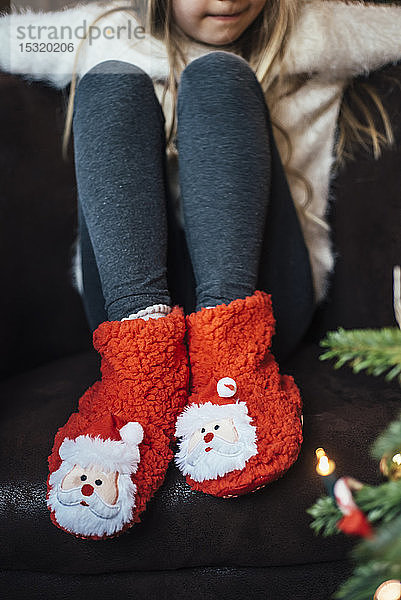 Nahaufnahme eines Mädchens in kuscheligen Weihnachtsmann-Schuhen