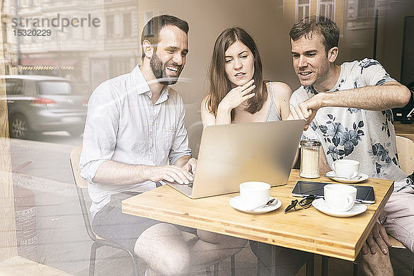 Gruppe von Freunden sitzt mit Laptop in einem Cafe zusammen