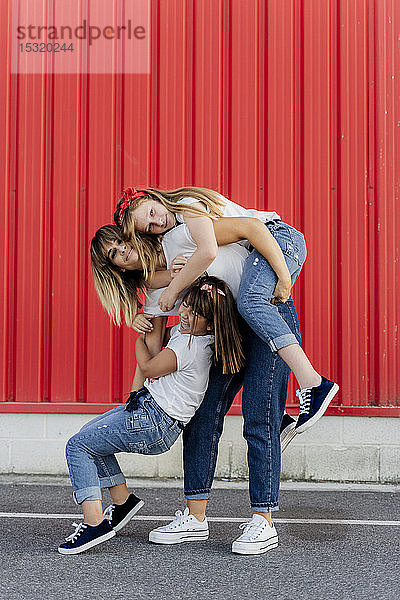 Mutter spielt mit ihren Töchtern vor der roten Wand