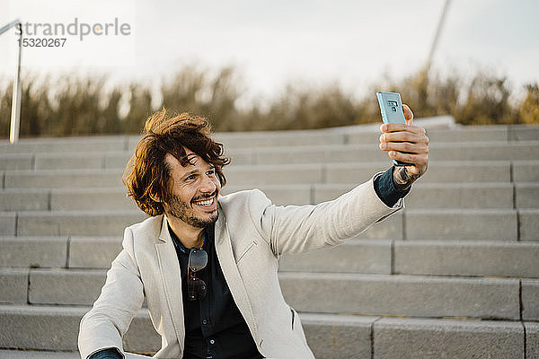 Porträt eines Geschäftsmannes  der sich mit einem Smartphone selbstständig macht