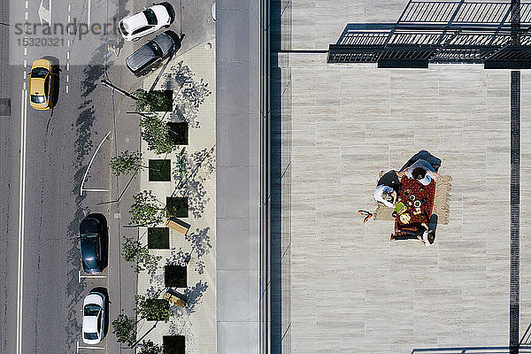 Luftaufnahme von drei Personen bei einer Mahlzeit auf dem Dach