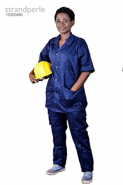 Junger lächelnder Bauarbeiter  der seinen Helm auf weißem Hintergrund hält