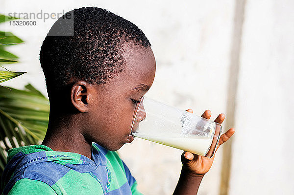 Der Junge trinkt Milch aus einem Glas.