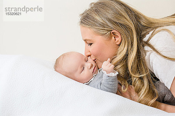 Zärtliche Nahaufnahme einer hübschen Mutter  die ihr 2 Monate altes Baby küsst.