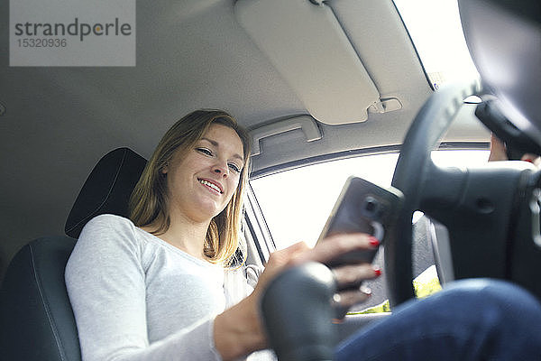 Junge Frau benutzt ihr Smartphone im Auto