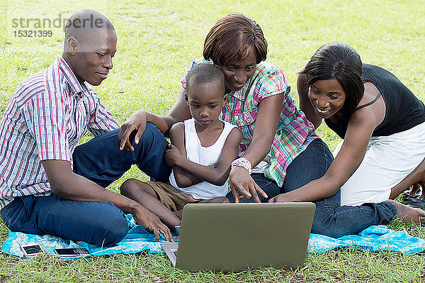 Eine Gruppe von Freunden und ein Kind schauen auf einen Laptop-Bildschirm.