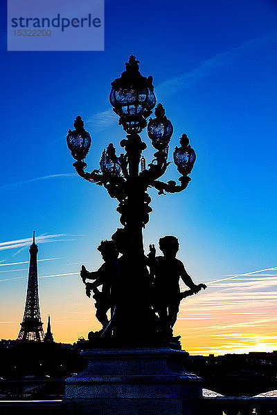 Frankreich  Paris  Pont Alexandre III  5. Oktober 2018: Sonnenuntergang auf dem Eiffelturm  von einem Laternenpfahl und Statuen 'Runde Liebe'