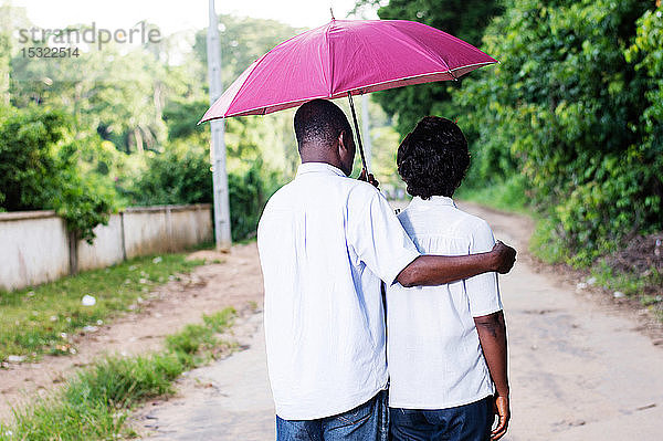 junge Paare flanieren und sind von einem Regenschirm bedeckt.
