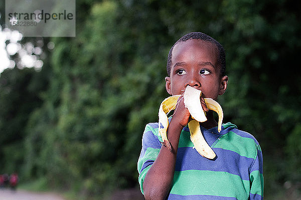 glücklicher kleiner Junge  der eine Banane isst.